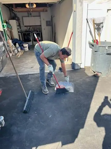 Crew member sweeping the driveway outside a cleared garage