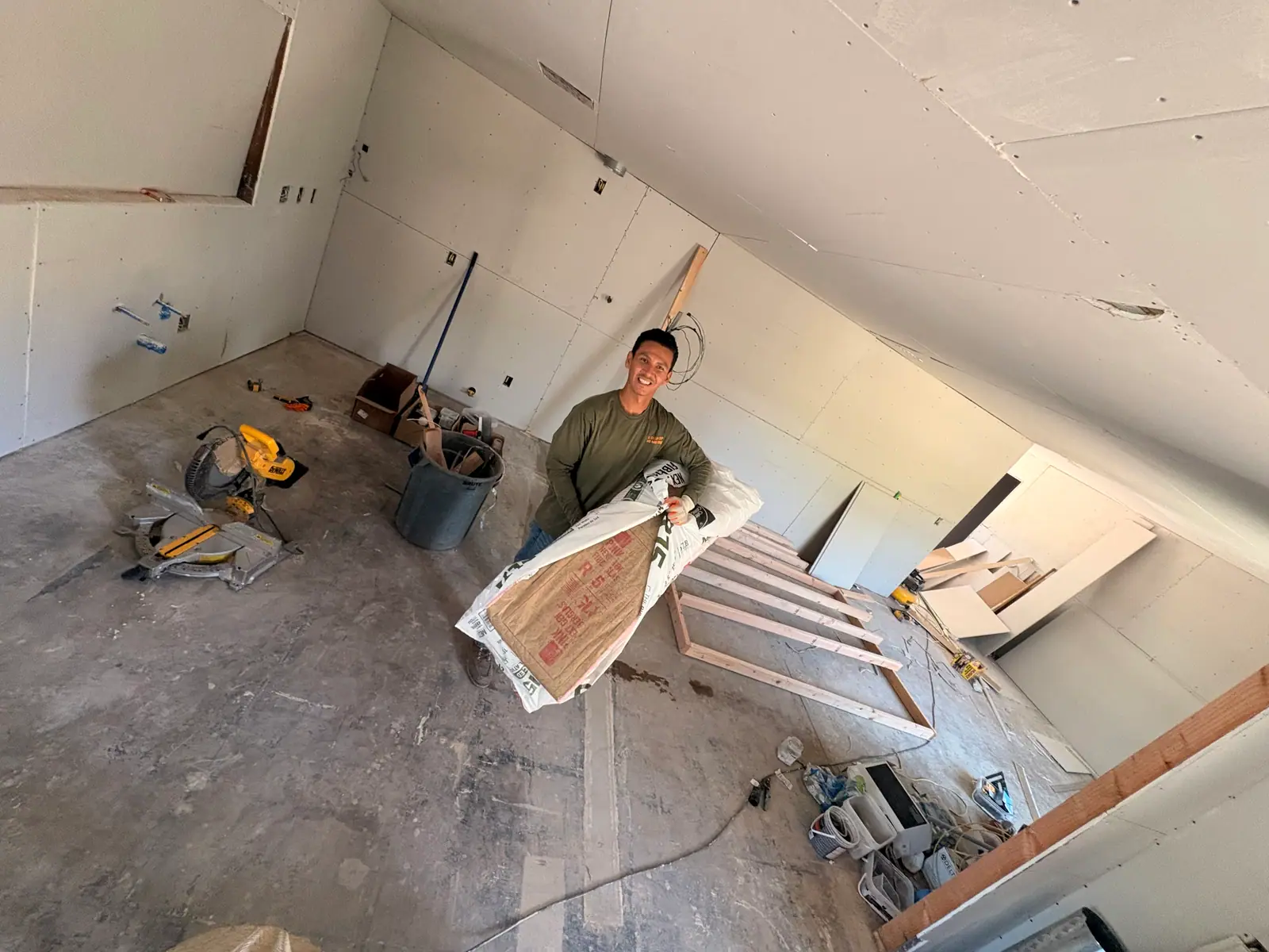 Smiling crew member carrying a bag of insulation scrap through a cleared room